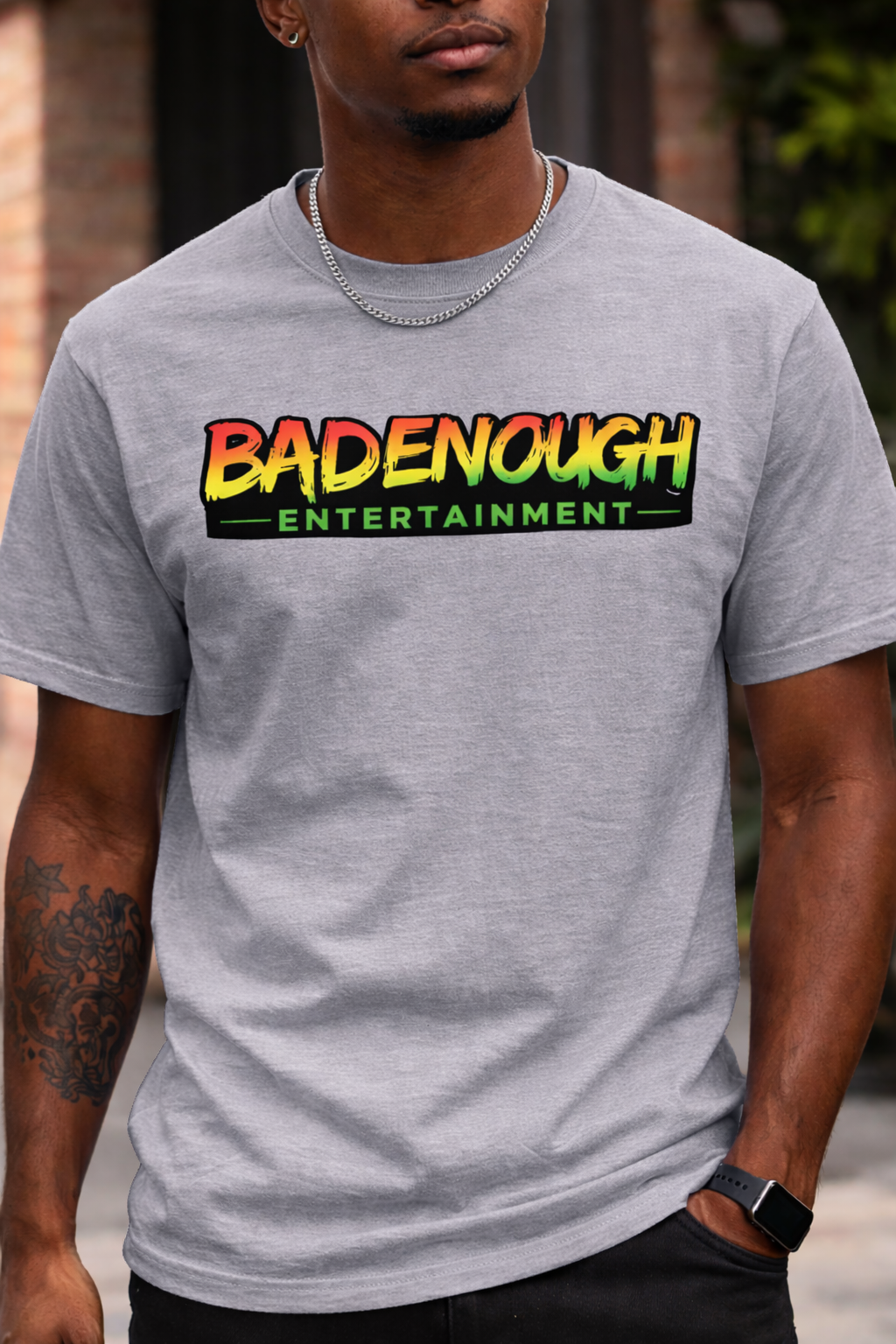 Man wearing a gray t-shirt with 'BADENOUGH ENTERTAINMENT' text design.