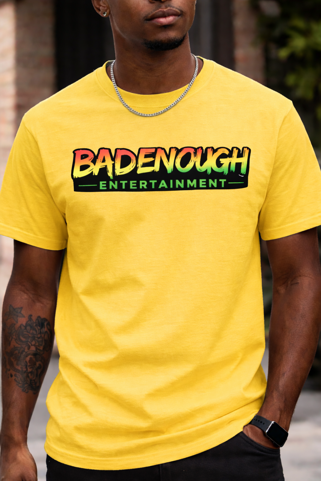 Person wearing a yellow t-shirt with 'BADENOUGH ENTERTAINMENT' text.